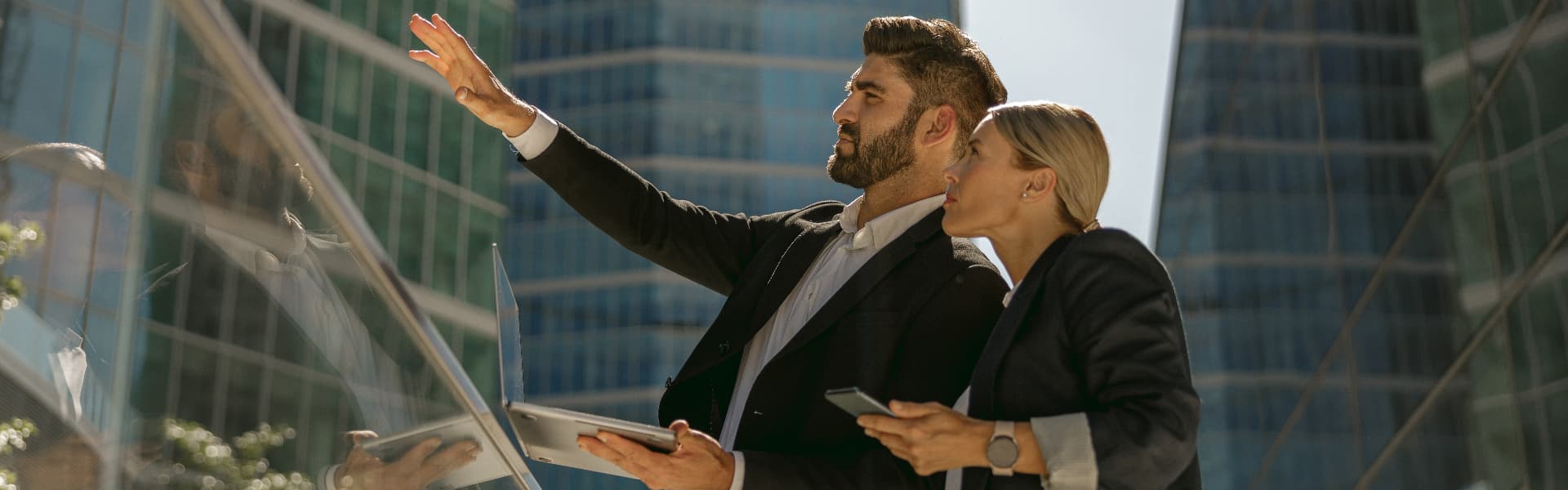 Two leaders reviewing plans outside a glass office tower