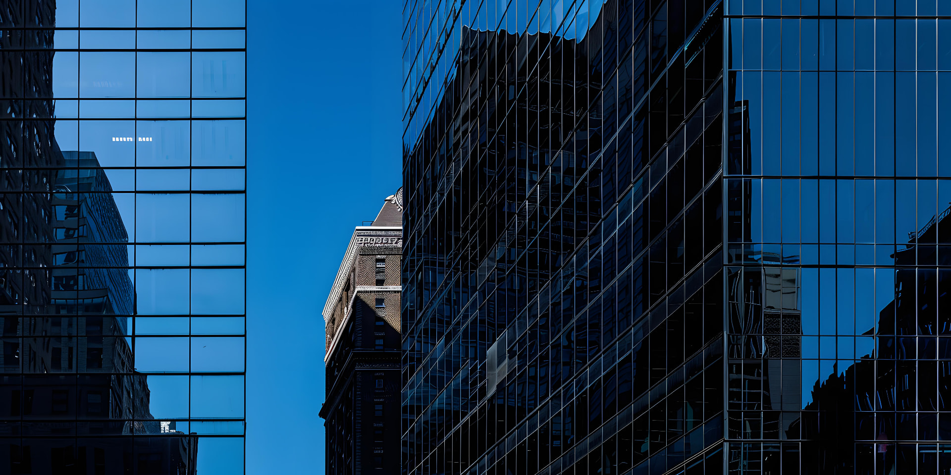 Glass office towers reflecting a clear blue sky