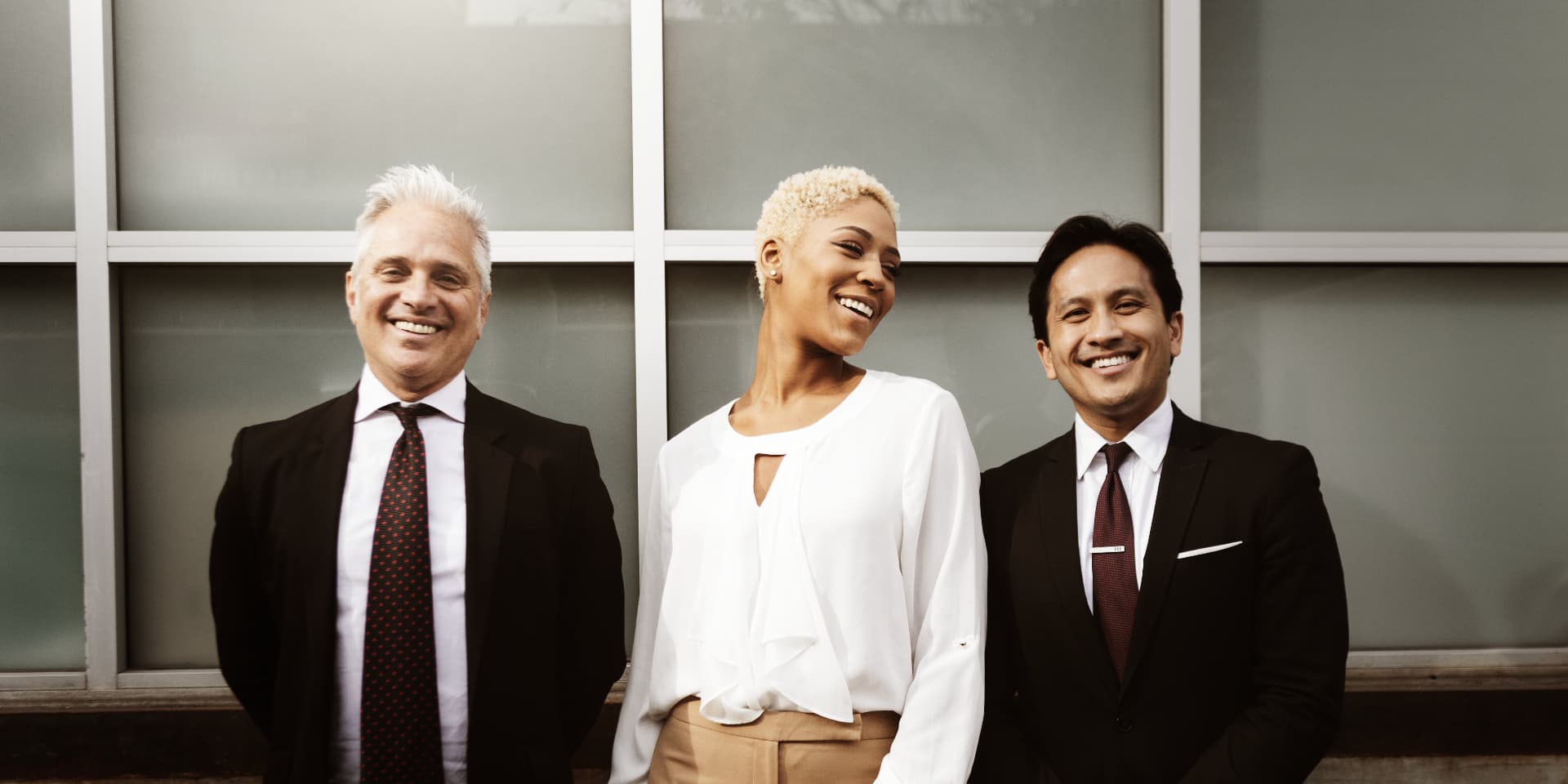 Three business leaders standing together outside a modern office